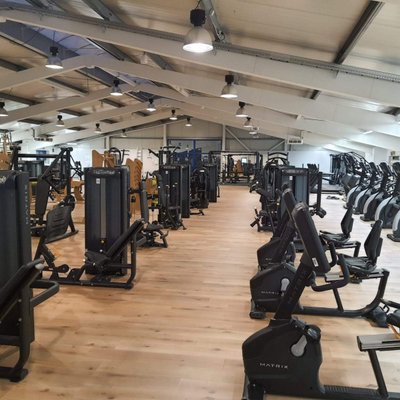 Moderner Fitnessraum mit verschiedenen Trainingsgeräten und Cardio-Maschinen.