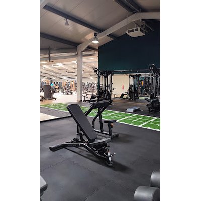 Trainingsbereich im Fitnessstudio mit Schrägbank und grüner Trainingsfläche im Hintergrund.