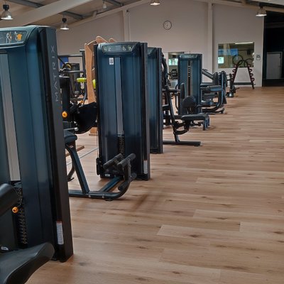 Moderner Fitnessraum mit verschiedenen Trainingsgeräten und Cardio-Maschinen.